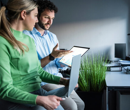 Colleagues brainstorming with tablet and laptop in the office