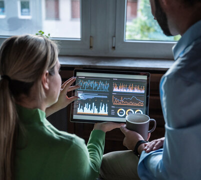 Colleagues analyzing finance data on a tablet indoors at the office