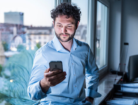 Businessman reading message on mobile device in the office