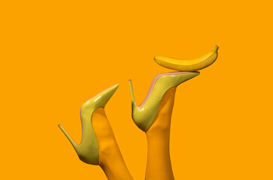 Surreal yellow scene with legs in heels balancing banana creative humor