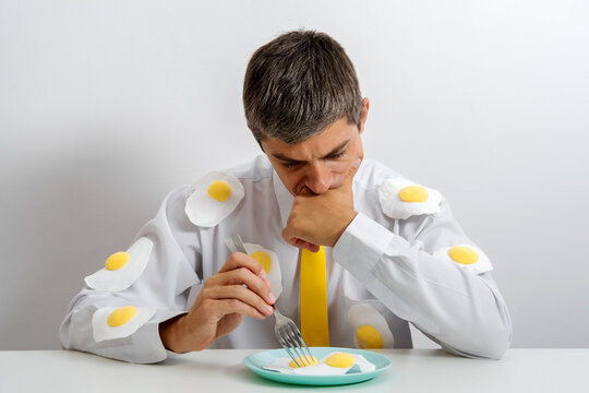 Office worker in white shirt with fried eggs looking introspective at breakfast