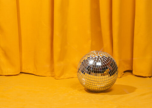 Disco ball on yellow fabric with curtain background for party concept