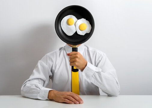 Office worker holding pan with fried eggs in humorous surreal portrait
