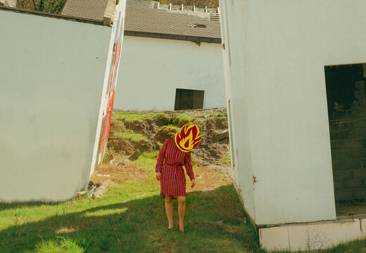 Figure wearing fire mask standing outdoors in ruined architecture