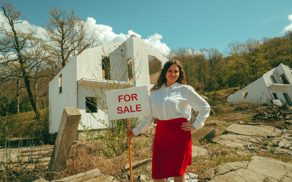 Realtor holding for sale sign by destroyed house