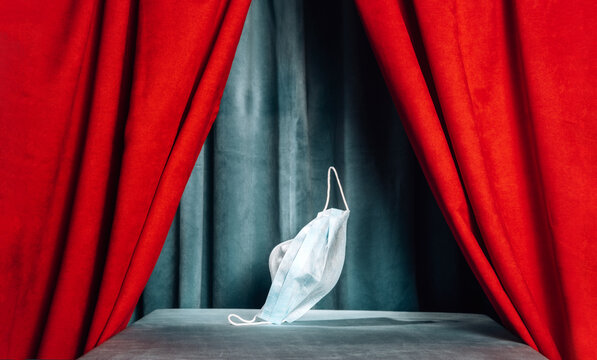 Medical mask on empty theater stage with red curtain