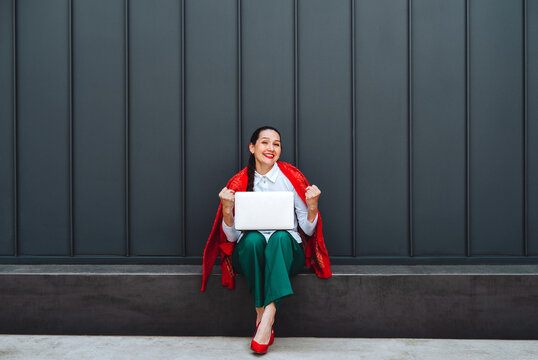 Freelancer celebrating success with laptop outdoors