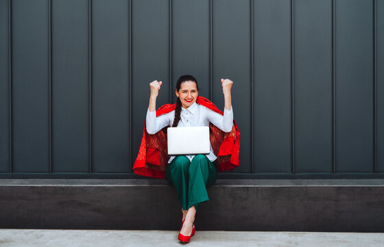 Cheerful freelancer celebrating success with laptop outdoors