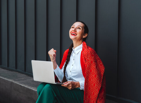 Happy freelancer celebrating success with laptop outdoors