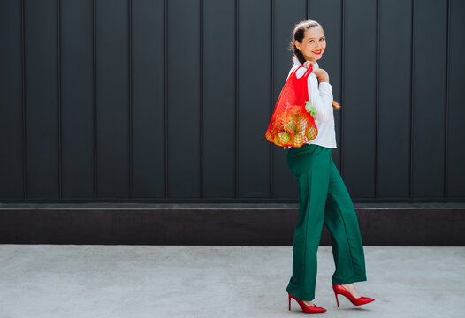 Shopper walking outdoors with eco friendly net bag of fruit