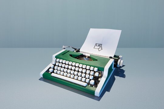 Green retro typewriter printing a save floppy disk icon