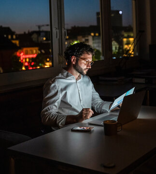 Professional working on tablet at office desk late at night