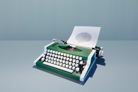 Retro green typewriter typing a speech bubble on paper