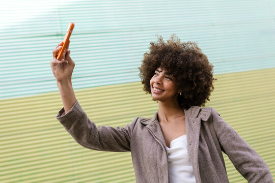 Smiling woman taking a selfie with smartphone outdoors