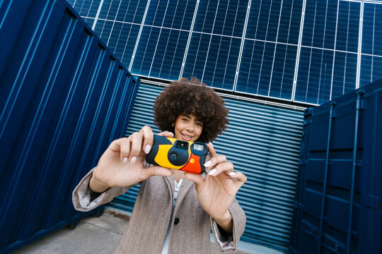 Cheerful photographer with camera by solar panels