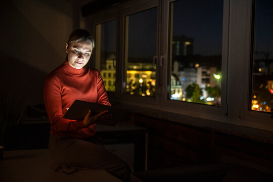 Businesswoman working on tablet in dark office at night