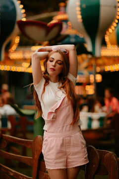 Model posing at an illuminated amusement park fairground