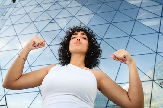 Confident model flexing biceps outdoors showing empowerment