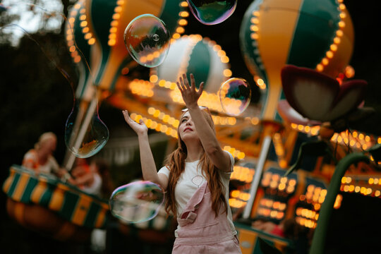 Catching a large soap bubble at an illuminated amusement park