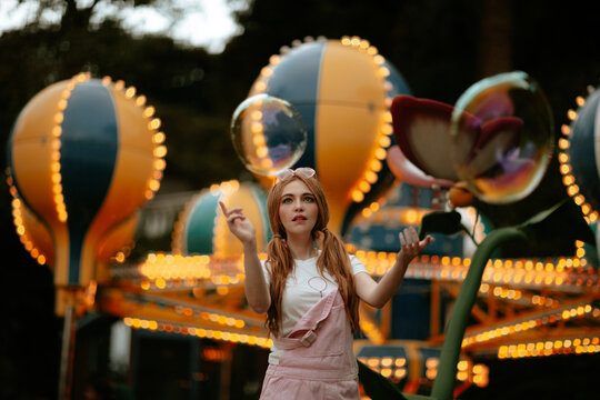 Woman playing with giant bubble at illuminated amusement park