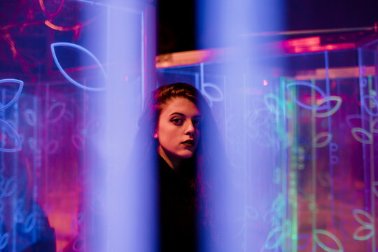 Mysterious portrait looking through glowing blue neon lights