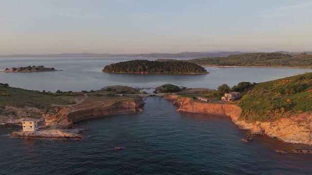 Aerial view of the coastline featuring rocky cliffs and lush green islands surrounded by calm blue waters at Zvernec, Vlore County, Albania.