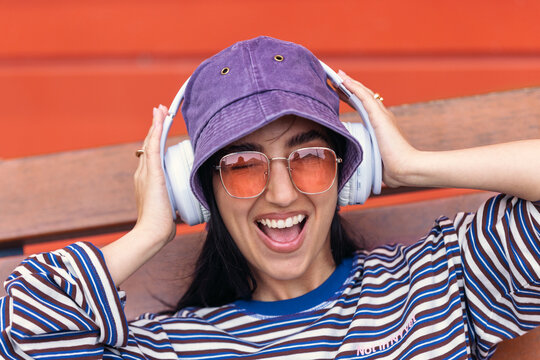 Smiling music fan with hat listening to headset