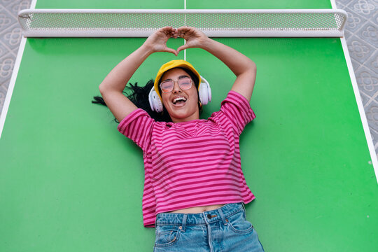 Smiling woman listening to music on outdoor table tennis table