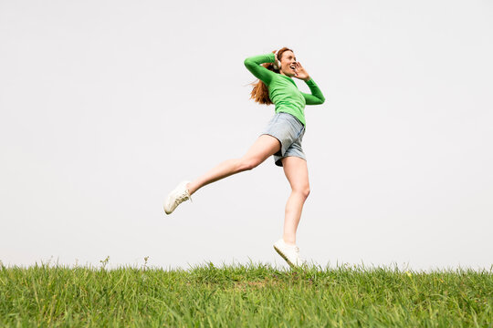 Person jumping with headphone in green field in Spain