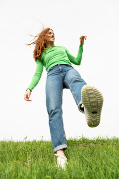 Smiling redhead in green shirt stepping on grass in Granada Spain