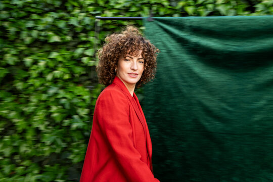 Model with curly hair posing in an orange blazer outdoors in Granada