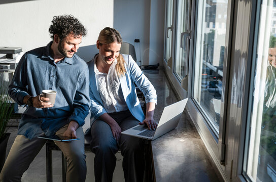 Colleagues working on a notebook by the office window