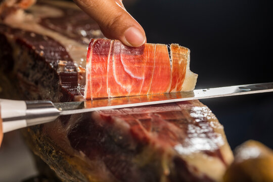 Hand slicing a thin slice of Iberian ham with a professional knife