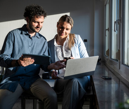 Business team working on a notebook and tablet in a sunny office
