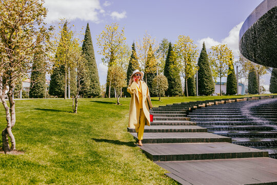 Happy freelancer in yellow suit walking outdoors in a modern park