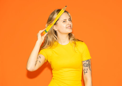 Artist holding large pencil brainstorming on orange background