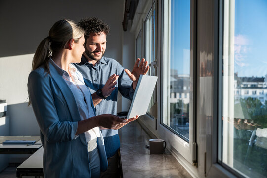 Business team brainstorming with laptop by office window