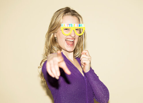Woman laughing and pointing with happy birthday prop