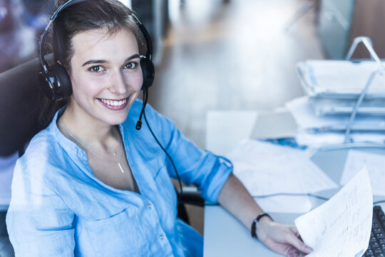 Smiling businesswoman with headset holding document in the office
