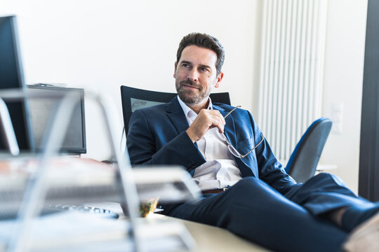 Confident businessman relaxing at desk in the office
