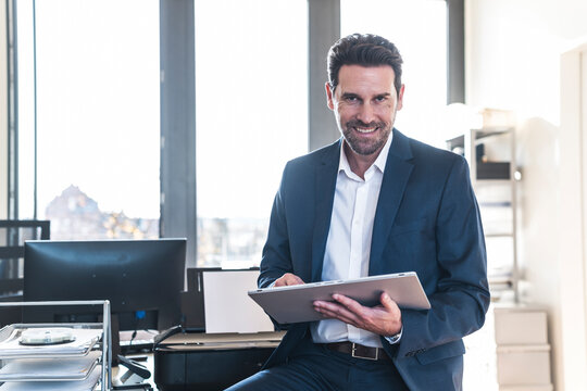 Smiling businessman holding tablet in the office
