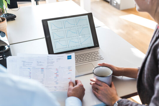 Businesspeople brainstorming with chart and notebook in office