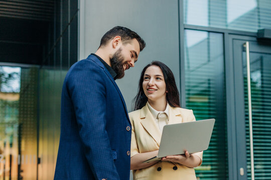Businessman and businesswoman using laptop outside