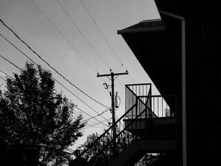 Silhouette d'une ligne électrique sur fond de ciel noir et blanc. Un poteau avec des fils électriques. © Pascal Huot