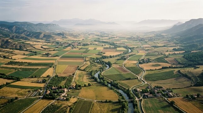 Scenic aerial view of vast agricultural valley with mountains background.