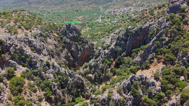 Flying over a deep rocky canyon with Mediterranean vegetation under summer sun