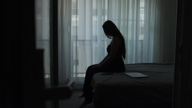 Expat woman sitting alone in temporary apartment feeling emotionally exhausted from constant relocation, homesickness and lack of belonging