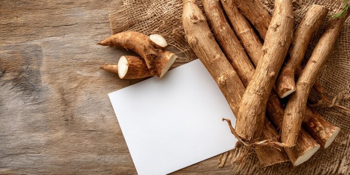 Raw cassava roots with white card on wooden surface top view for conceptual design