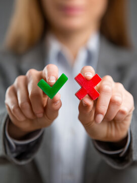 Businesswoman holding green approval check mark and red rejection cross symbol representing decision making and right versus wrong choices in professional setting