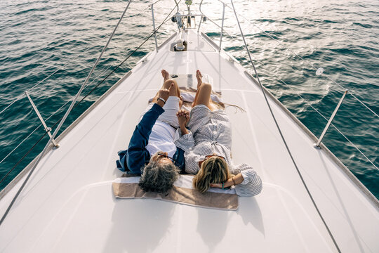 Senior couple relaxing on yacht deck pointing to horizon